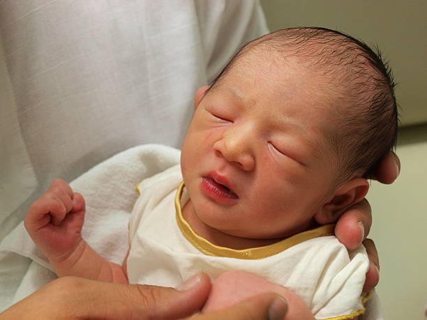 nouveau-né bébé dans la main - baby yawning asian ethnicity newborn photos et images de collection