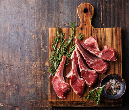 Raw fresh Lamb Meat ribs and seasonings on dark wooden background