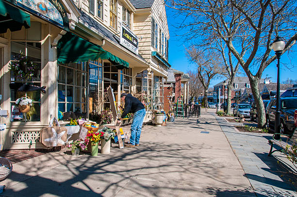 Painting the scene Falmouth, Massachusetts, Unitet States - April 21, 2013: Painting the scene. A painter, armed with his easel, is dedicated to paint a picture on Main Street in Falmouth, Massachusetts, a sunny spring day. In the background, two women are walking down the sidewalk. tarde stock pictures, royalty-free photos & images