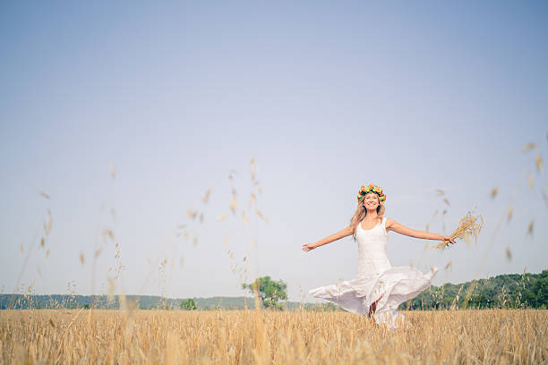 happy young woman standing with open arms in the field, selective focus, vintage color editing