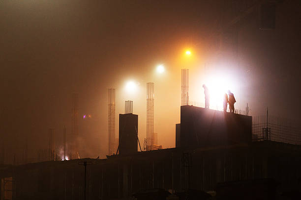 Beautiful view of the construction site cyurrealistichny high-rise building at night in the fog in the spotlight truck crane. Close fog creates the effect of film grain.