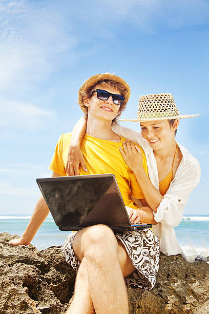 istock Happy couple with their laptop on the beach 528796617