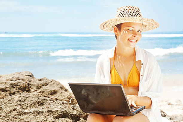 istock Young woman with her laptop on the beach 528807813