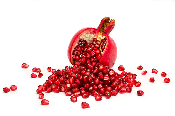 istock pomegranate with scattered grains on white background. 528826365
