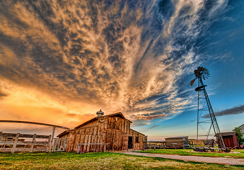 An farmstead barn and windmill at sunset.