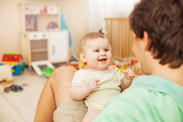 vater sein baby füttern fröhlich - child playroom parent indoors stock-fotos und bilder