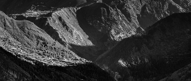 Monochrome landscape panorama across the dramatic mountain clifts, forest and remote Sherpa villages of Phortse and Phunka Tenga deep in the Khumbu valley of the Everest National Park, Nepal, a UNESCO World Heritage Site. ProPhoto RGB profile for maximum color fidelity and gamut.