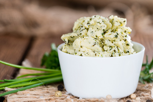 Portion of fresh made herb butter on rustic wooden background
