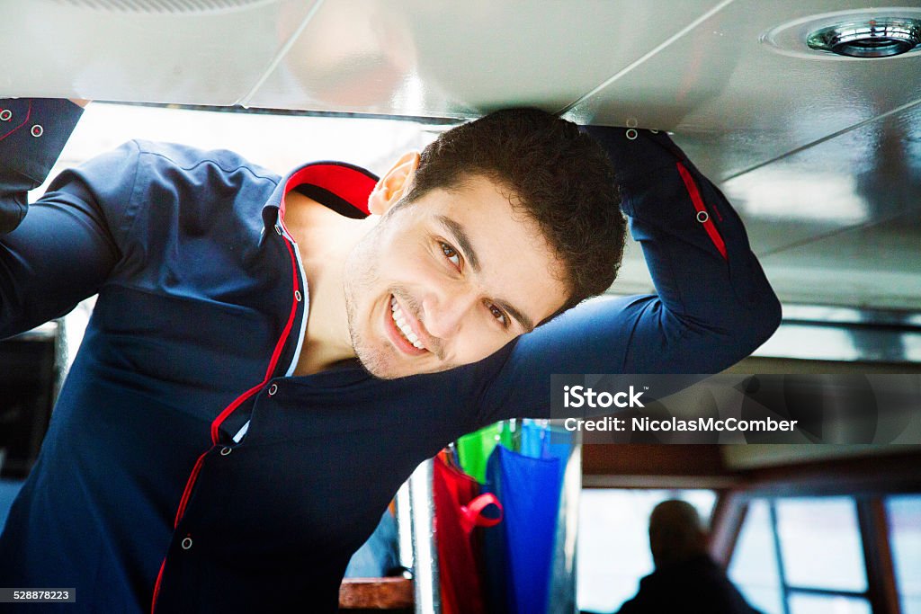 Young man entering yacht cabin from top deck smiling Young man entering yacht cabin from top deck smiling at camera as he climbs down the stairs. 20-24 Years Stock Photo