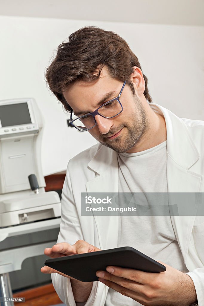 At the Optician Ophthalmologist In Exam Room Using Digital Tablet Ophthalmologist Stock Photo