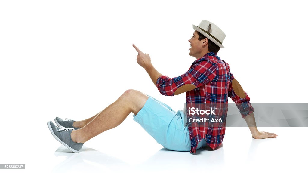 Smiling man sitting on floor & pointing away Smiling man sitting on floor & pointing awayhttp://www.twodozendesign.info/i/1.png 20-29 Years Stock Photo