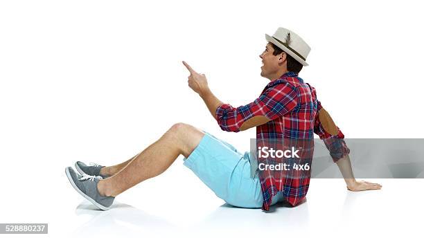 Smiling Man Sitting On Floor Pointing Away Stock Photo - Download Image Now - 20-29 Years, Adult, Adults Only