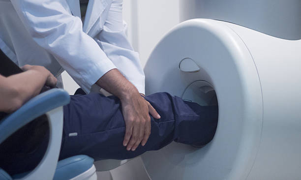 Patient and Doctor in fully open MRI CAT Scan Patient and Doctor in fully open high field Magnetic Resonance Image MRI CAT Scan scanning knee and leg. human knee stock pictures, royalty-free photos & images