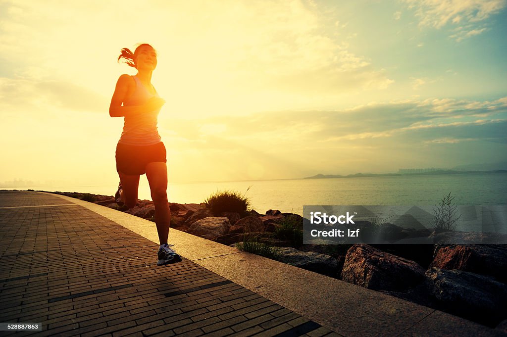 healthy lifestyle asian woman running at sunrise seaside Running Stock Photo