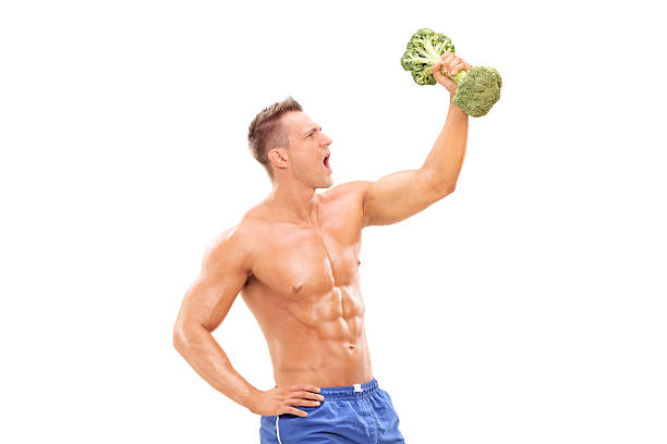 Handsome athlete lifting a broccoli dumbbell Handsome athlete lifting a broccoli dumbbell isolated on white background eating body building muscular build vegetable stock pictures, royalty-free photos & images