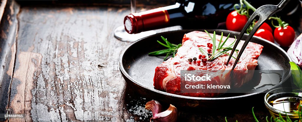 Raw beef steak and wine Marbled beef steak  with a bottle of wine and vegetables on old wood background Animal Blood Stock Photo