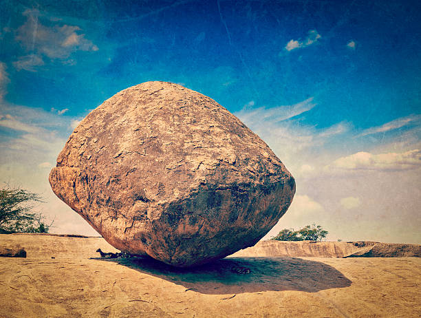 Vintage retro hipster style travel image of Krishna's butterball -  balancing giant natural rock stone with grunge texture overlaid. Mahabalipuram, Tamil Nadu, India