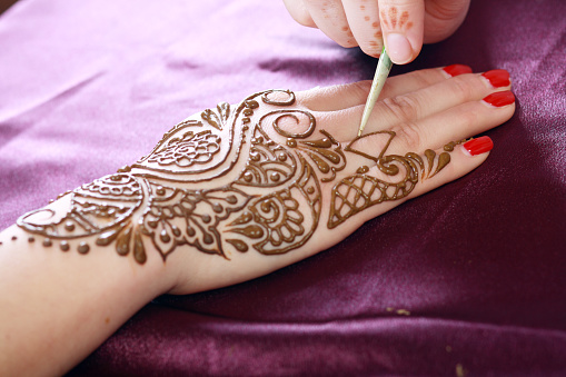 Image detail of henna being applied to hand close up