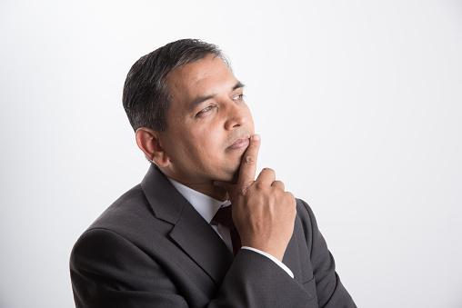indian mid age businessman thinking, handsome asian businessman thinking, indian businessman with one hand folded and one hand touching chin, thinking, isolated over white background