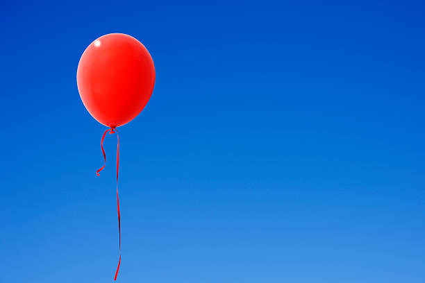 istock Red balloon moving up in the clear sky 528892327