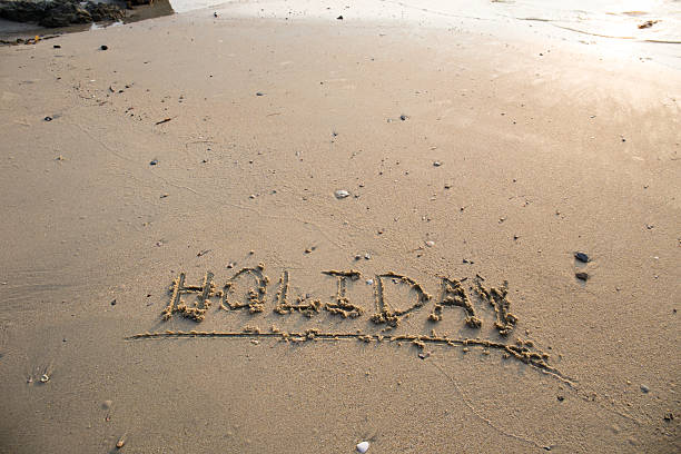 istock Holiday written in the sand at the beach 528895508