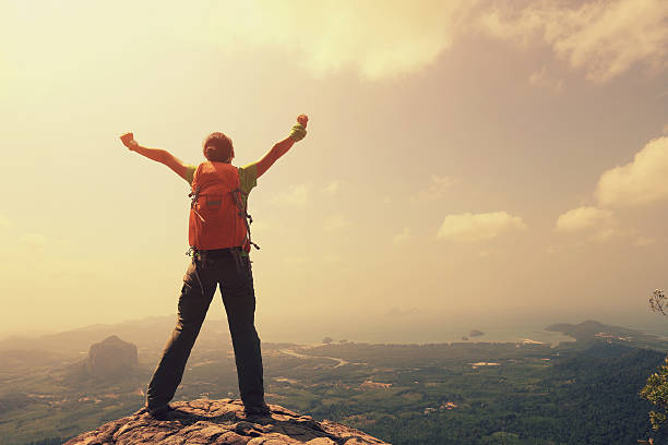 istock cheering woman hiker open arms at mountain peak 528901856