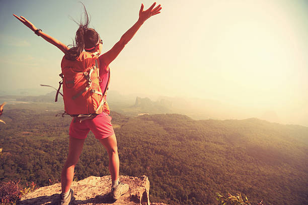 istock cheering successful woman hiker open arms at mountain peak 528905164