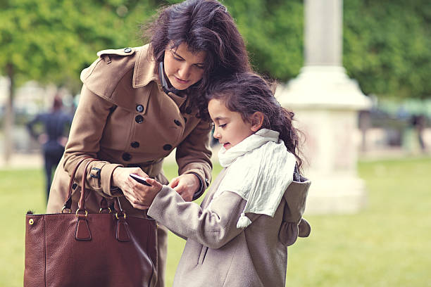 Brunette mother daughter walking in Paris park on spring afternoon Brunette mother daughter walking in Paris park on spring afternoon divorcee stock pictures, royalty-free photos & images