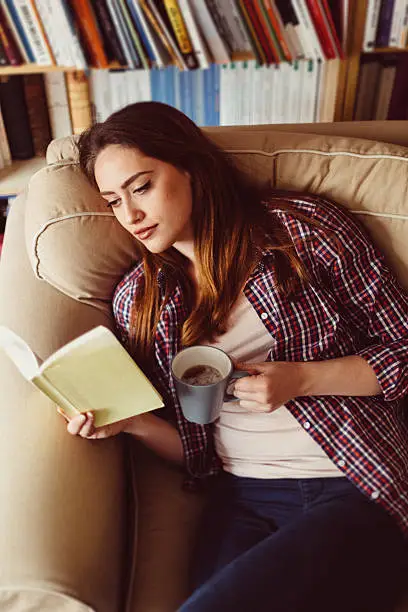 Photo of Girl in sofa reading a book