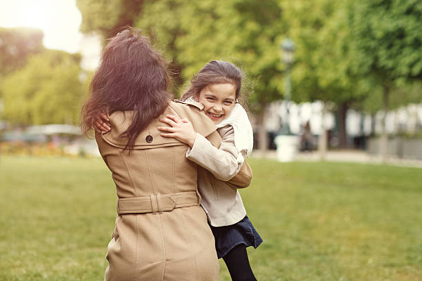 Brunette mother daughter hugging in Paris park on spring afternoon Brunette mother daughter hugging in Paris park on spring afternoon divorcee stock pictures, royalty-free photos & images