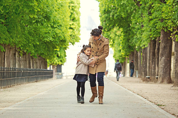 Brunette mother daughter walking in Paris park on spring afternoon Brunette mother daughter walking in Paris park on spring afternoon divorcee stock pictures, royalty-free photos & images