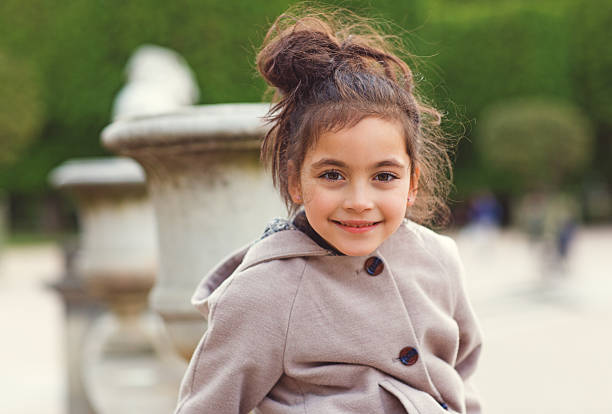 Close-up of cute little girl in a cap and a jacket in nature during an autumn day