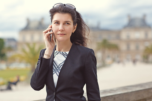 Beautiful brunette business woman walking through Paris gardens