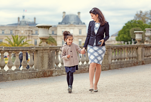 Brunette mother daughter walking in Paris park on spring afternoon