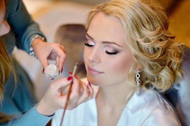 Wedding makeup artist making a make up for bride Wedding makeup artist making a make up for bride. Beautiful sexy model girl indoors. Beauty woman with curly hair. Female portrait. Bridal morning of a cute lady. Close-up hands near face ceremonial make up photos stock pictures, royalty-free photos & images