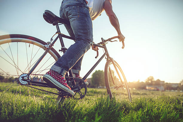 Hipster  guy riding his bicycle on the grass, in a city park