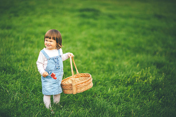 Adorable baby girl having fun with basket outdoors on her house terrace on a sunny summer day.