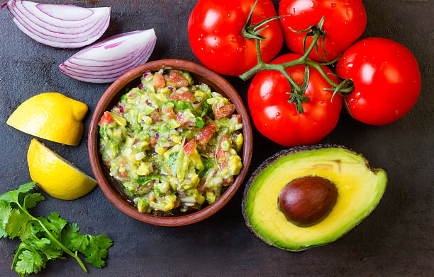 guacamole und zutaten-avocado, tomaten, zwiebeln, koriander, dunklen hintergrund. - guacamole stock-fotos und bilder