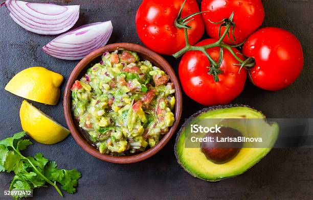 Guacamole And Ingredients Avocado Tomatoes Onion Cilantro Dark Background Stock Photo - Download Image Now