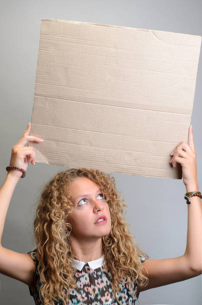 istock girl holding blank board on grey background 528913140