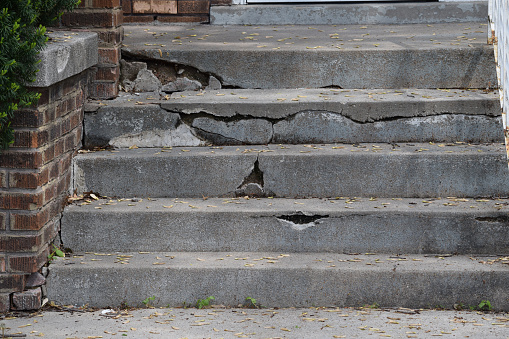 Short set of cement steps is cracked and broken and in need of repair