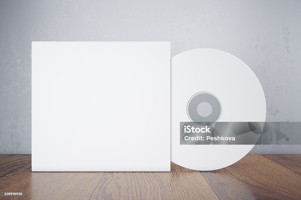 Blank white disk Blank white compact disk with cover on wooden table and concrete wall background. Mock up, 3D Rendering Compact Disc Stock Photo