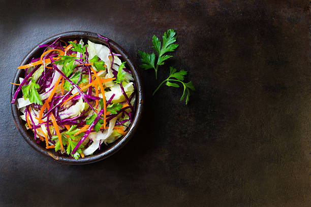 Fresh vegetables salad purple cabbage, lettuce, carrot. Top view Fresh vegetables salad with purple cabbage, white cabbage,  lettuce, carrot in dark clay bowl on black background. Top view coleslaw stock pictures, royalty-free photos & images