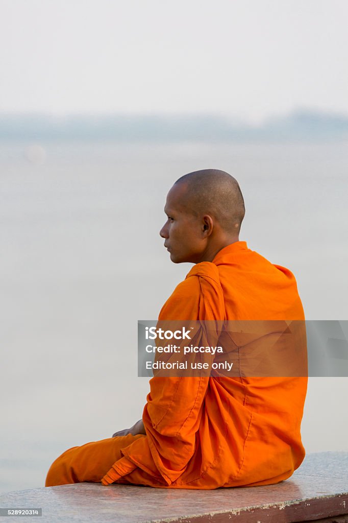 Orange dressed Cambodian monk looking at the Mekong, Phnom Penh - Royaltyfri 20-29 år Bildbanksbilder