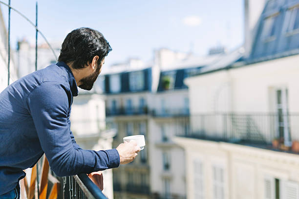 istock Young Man With Coffee on a Sunny Balcony 528921934