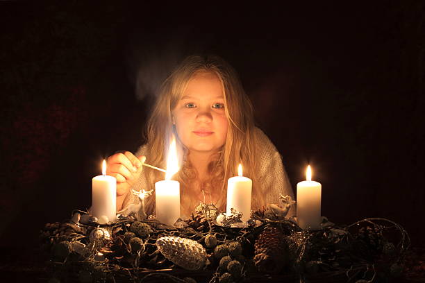 Blonde girl lighting up an Advent wreath candle stock photo