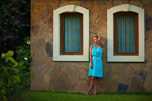 Beautiful girl in blue dress near the wall stock photo