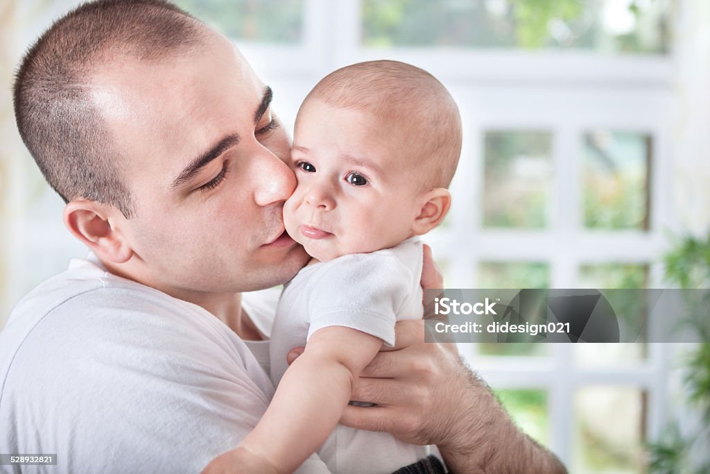 Gentle young father comforting crying baby Gentle father comforting crying baby Adult Stock Photo