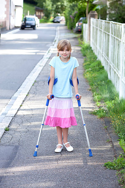 giovane ragazza con le stampelle su strada sorridente - disablement foto e immagini stock