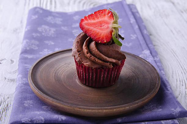 istock Chocolate cupcakes with strawberry on a wooden table. 528953558